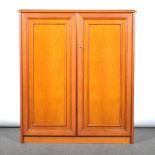 A modern cherry veneered tallboy, with pair of panelled doors, enclosing tw