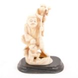 An ivory okimono of an elderly gentleman with two monkeys and a staff.10cm
