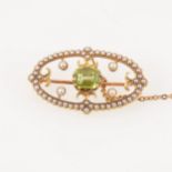 A green peridot and seed pearl brooch set in a yellow metal oval frame setting, 30mm x 17mm.