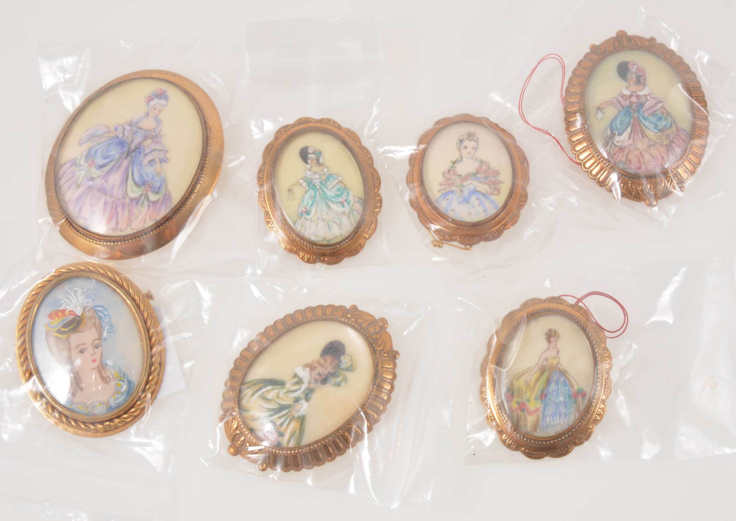 Thomas L Mott - seven hand painted oval portrait brooches of ladies in crinoline costumes.