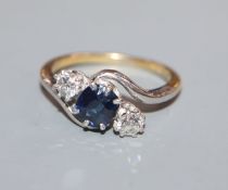 An 18ct, sapphire and diamond three stone crossover ring, size K.