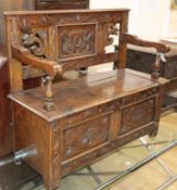 An 18th century style carved and panelled oak monk's bench W.100cm