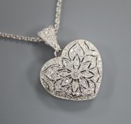 A modern pierced 18ct white gold and diamond encrusted heart shaped locket on an 18ct white gold