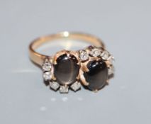 A yellow metal, twin stone cabochon cat's eye cabochon and diamond set crossover ring, size M.