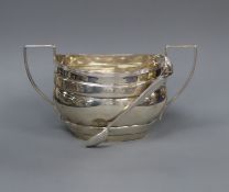 A George V silver two handled sugar bowl, Birmingham 1917 and a pair of plated tongs.