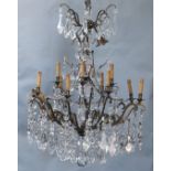 An Italian bronze and cut glass twelve light chandelier, hung with flower and lappet and tear shaped