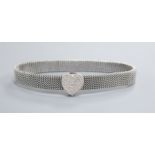 An expanding metal mesh bracelet with a 14k white metal and diamond encrusted heart shaped sliding