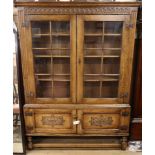 A reproduction carved and panelled oak bookcase, fitted astragal-glazed doors on stretcher base W.