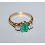 A modern 18ct gold, emerald and diamond three stone ring, size O.