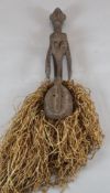 A tribal carved wood figure with sago palm leaf fringe, 66cm