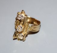 A 1970's? textured 18ct and three stone diamond set upfinger ring, size P.