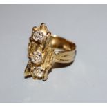 A 1970's? textured 18ct and three stone diamond set upfinger ring, size P.