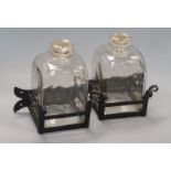 A pair of glass square decanters, on wrought iron stands