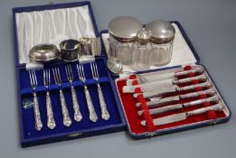 Two cased sets of silver handled tea knives and forks, three mounted toilet jars, two napkin