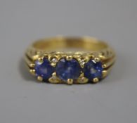 A modern Edwardian style 18ct gold and three stone sapphire ring with diamond chip spacers, size O.