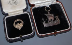 A cased white metal pendant modelled as a Viking ship and a cased gilt white metal Celtic brooch,