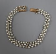 A 1920's? yellow metal, seed pearl and diamond set three strand bracelet, the clasp bearing the