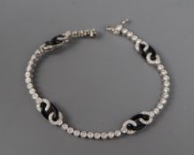 A modern 1920's style 18ct white gold and black onyx line bracelet, with oval motifs, 17.3cm.