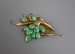 A 14k yellow metal and cabochon jade set stylised spray brooch, 57mm.