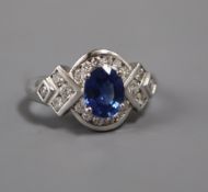 A modern 18ct white gold, sapphire and diamond oval cluster ring, with diamond set shaped shoulders,