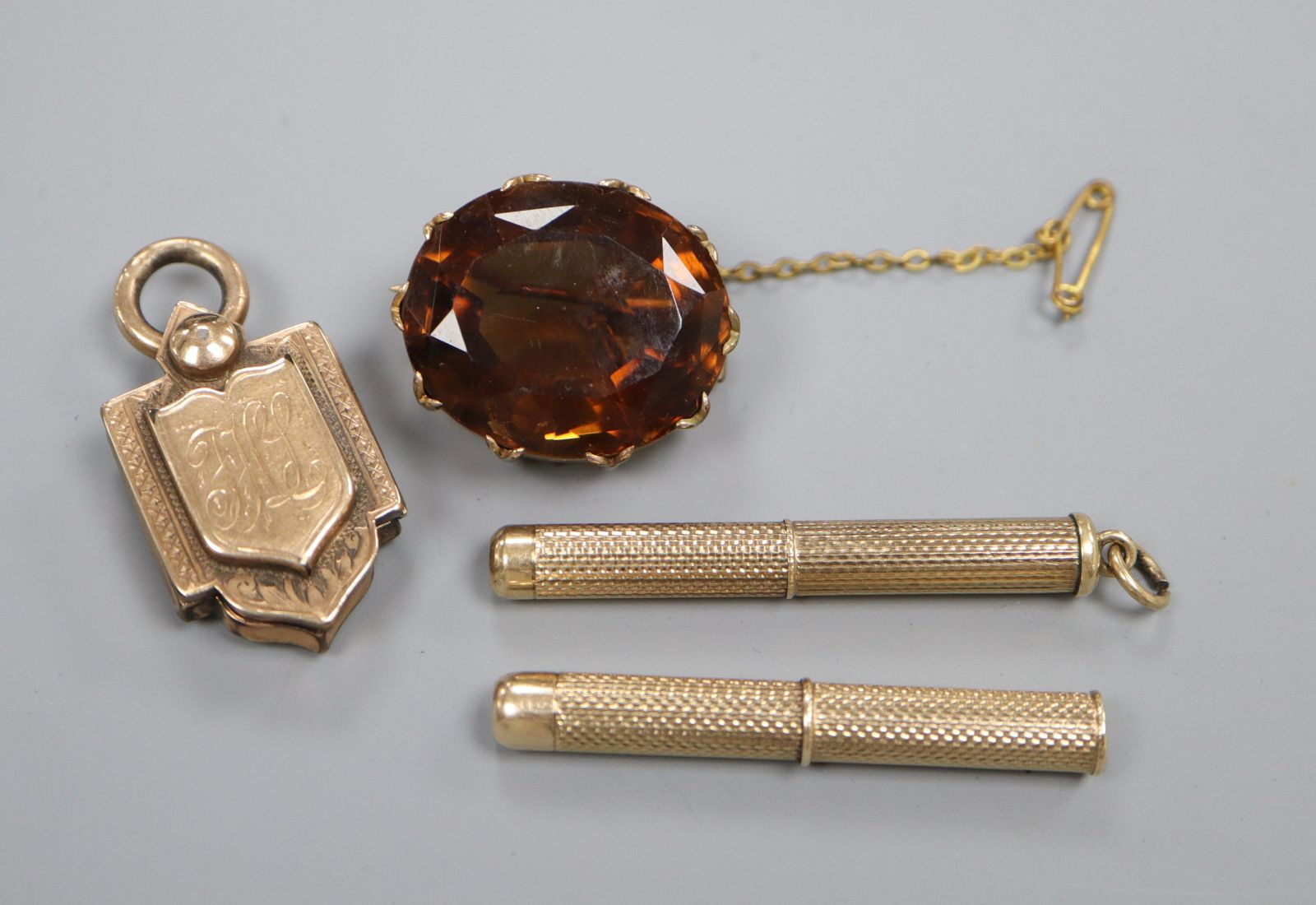 A Victorian yellow metal locket, two 9ct gold cased propelling toothpicks (one a.f.) and a brooch.