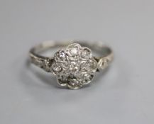 A 1920's white metal and diamond set flower head cluster ring, with diamond set shoulders, size H/