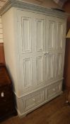 A large pale green painted two door hanging wardrobe, with two base drawers W.132cm