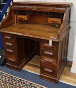 A 1920's oak five drawer tambour roll top desk W.106cm