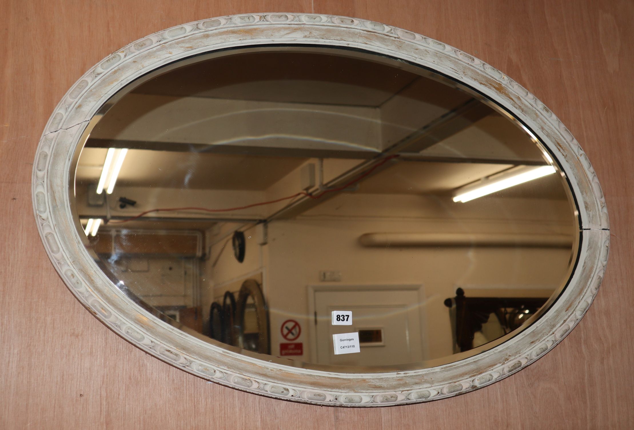 An oval white painted wall mirror W.100cm