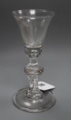 An early 18th century baluster wine glass, the bell bowl with solid lower section and tear inclusion