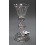 An early 18th century baluster wine glass, the bell bowl with solid lower section and tear inclusion