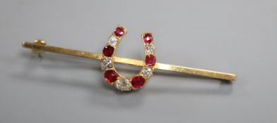 A modern 9ct gold, ruby and diamond set horseshoe bar brooch, 57mm.