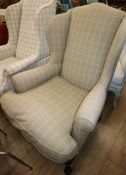 A George III style upholstered wing armchair on claw feet