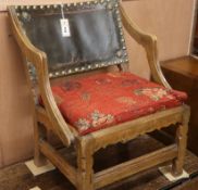 An Arts and Crafts-style oak low chair, with studded leather back