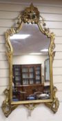 A large gilt-framed wall mirror, with shaped rectangular plate and ornate scrolled frame with