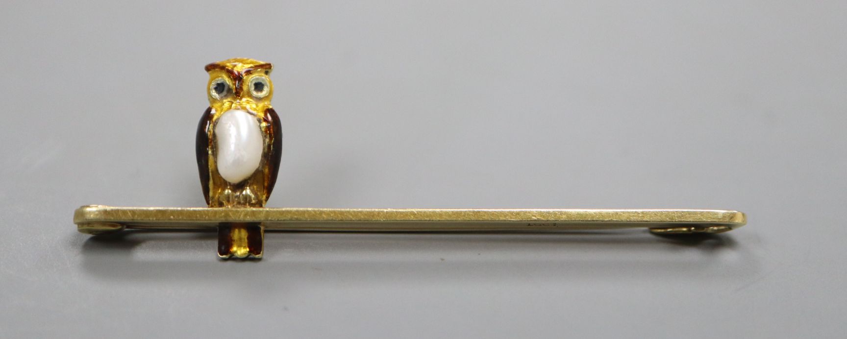 An Edwardian 15ct, enamel and baroque pearl set owl bar brooch, 52mm.