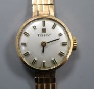 A lady's 9ct gold Tissot manual wind wrist watch, on a 9ct gold strap.