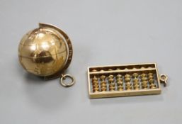 A yellow metal terrestrial globe charm and an abacus charm (both testing as 14ct), gross 23.3g.