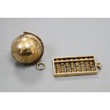 A yellow metal terrestrial globe charm and an abacus charm (both testing as 14ct), gross 23.3g.