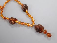 An amber necklace, with facetted beads and three carved Buddha, gross weight, 38 grams, 78cm.