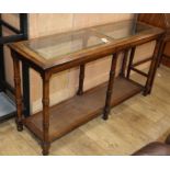 A reproduction walnut two tier side table, the top inset plate glass panels W.132cm