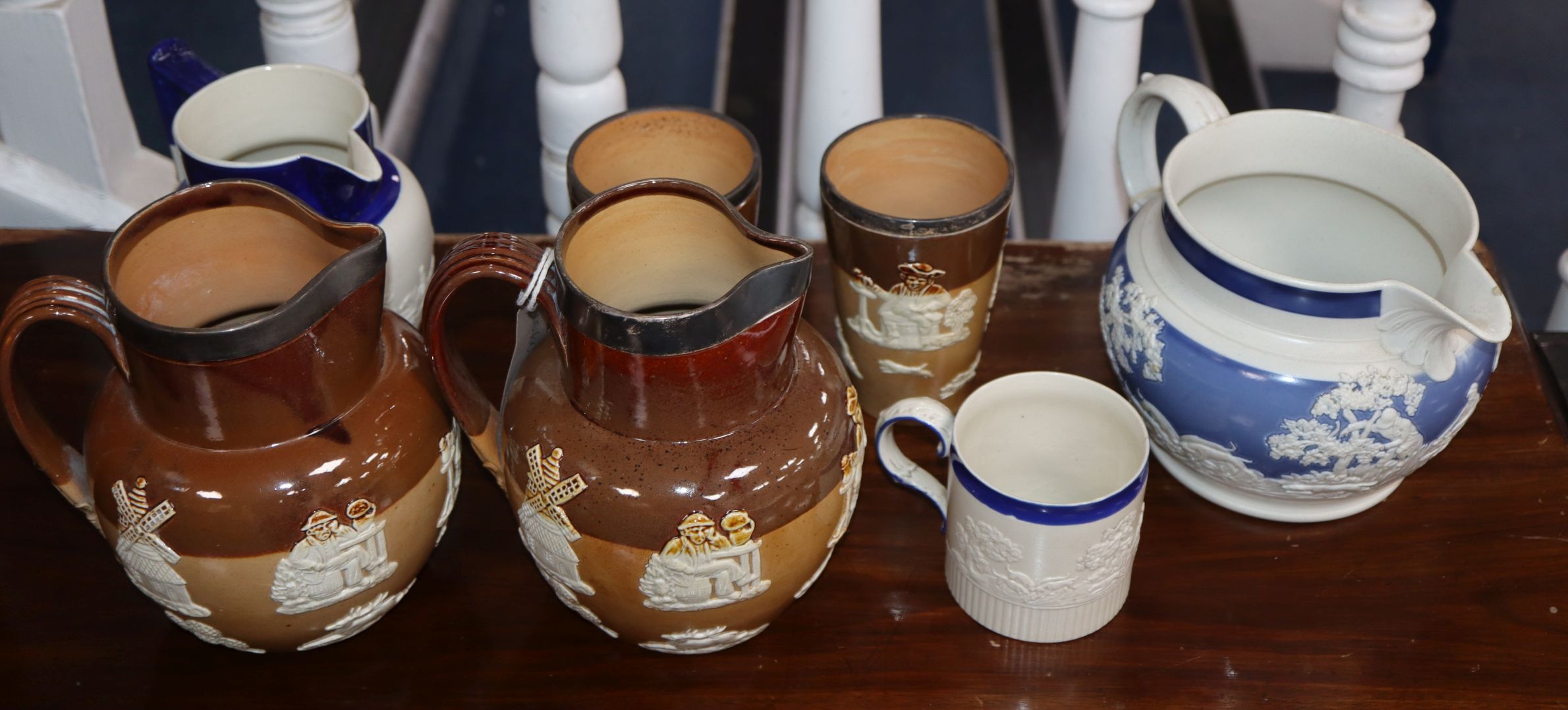 Two Doulton Lambeth jugs and two beakers with silver mounted rings and three white stoneware