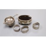 A George V silver trinket box, three serviette rings and a tea strainer and stand.
