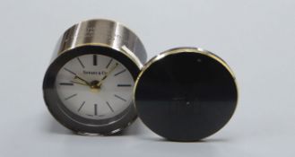 A Tiffany & Co gun metal grey metal promotional travel alarm clock with brass banding Diameter 6cm