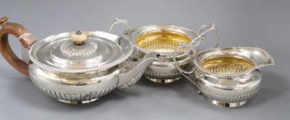 A matched silver three-piece tea service of flattened circular half-fluted form with gadrooned