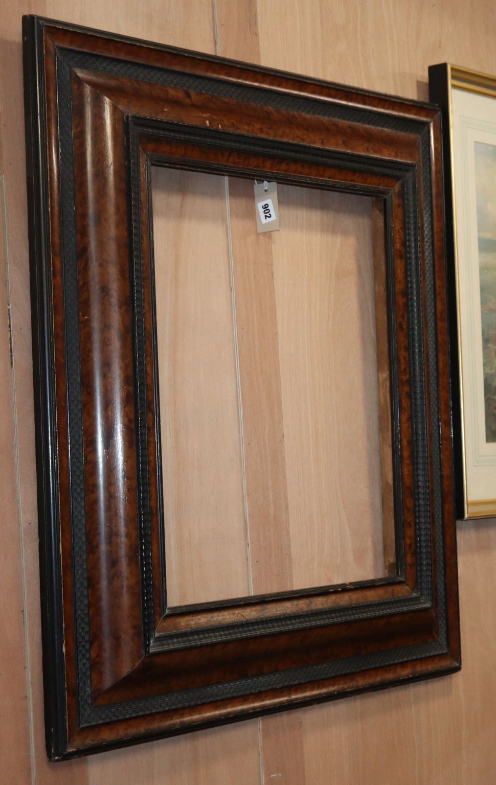 A 19th century Dutch brush grained and ebonised cushion frame wall mirror, lacking plate, W.2ft 7in.