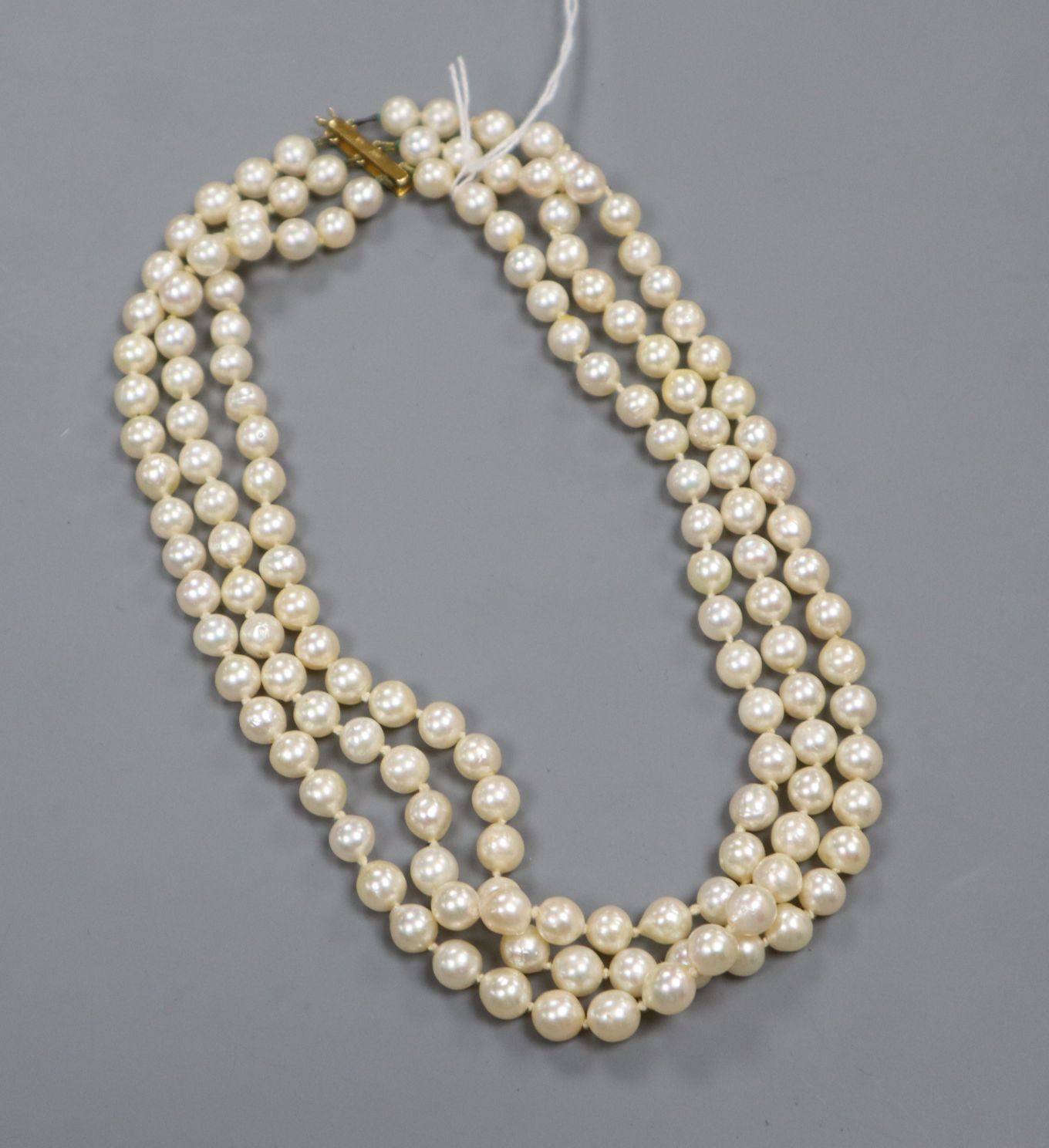 A triple strand cultured pearl necklace with 375 yellow metal clasp, approximately 46cm.