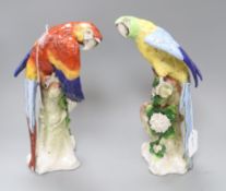 A pair of Sitzendorf Macaws, one red, one blue, each modelled perched on a naturalistic tree stump