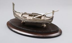 An early 20th century Maltese white metal model of a Dghajsa, with two oars, on stand, 13.4cm, 3.5