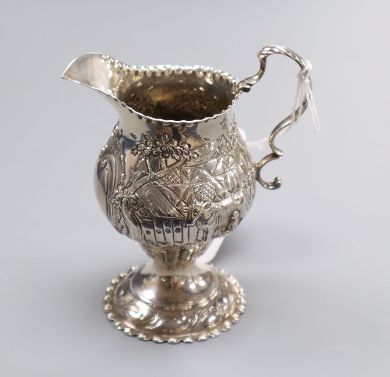 A George III silver cream jug, London, 1779, with later embossed decoration, 11.1cm.
